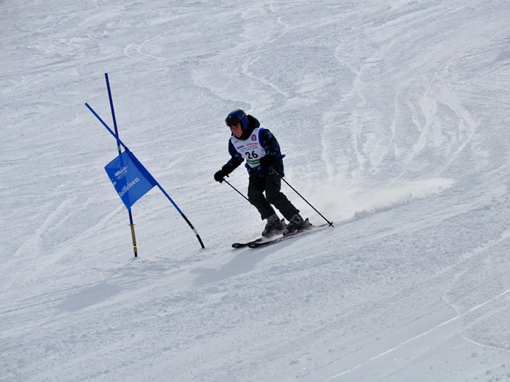Skifahrer umfährt ein blaues Tor auf der Rennstrecke.
